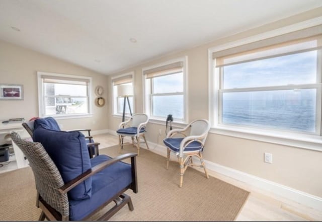 sitting room with a wealth of natural light, baseboards, lofted ceiling, and light wood-type flooring