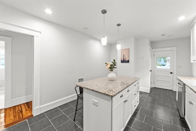 kitchen featuring light stone counters, decorative light fixtures, a center island, and white cabinets