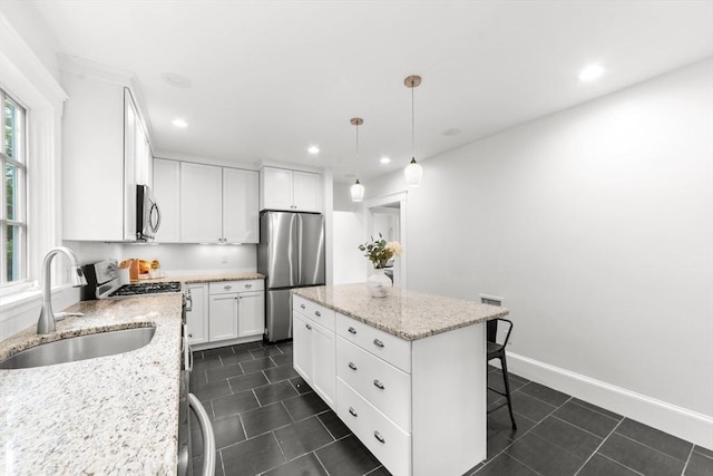 kitchen featuring a kitchen island, decorative light fixtures, white cabinetry, sink, and stainless steel appliances