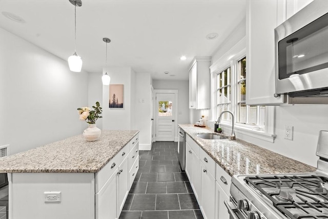 kitchen featuring sink, light stone counters, a kitchen island, stainless steel appliances, and white cabinets