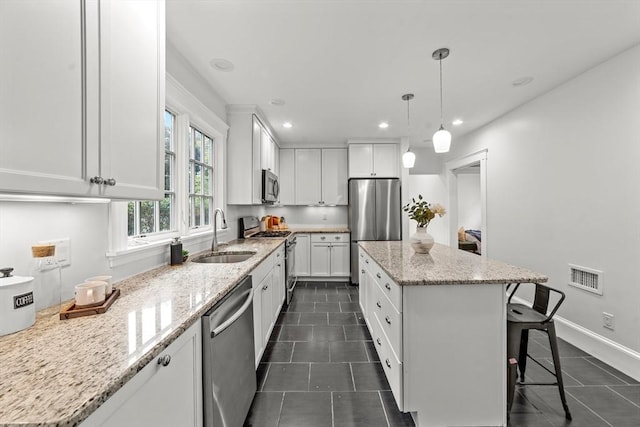 kitchen with white cabinetry, stainless steel appliances, a center island, and sink