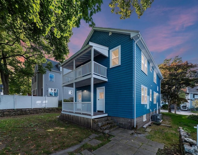 back house at dusk with a balcony and central AC unit