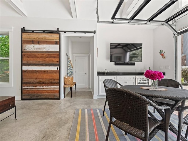 dining space featuring finished concrete floors, beverage cooler, and a barn door