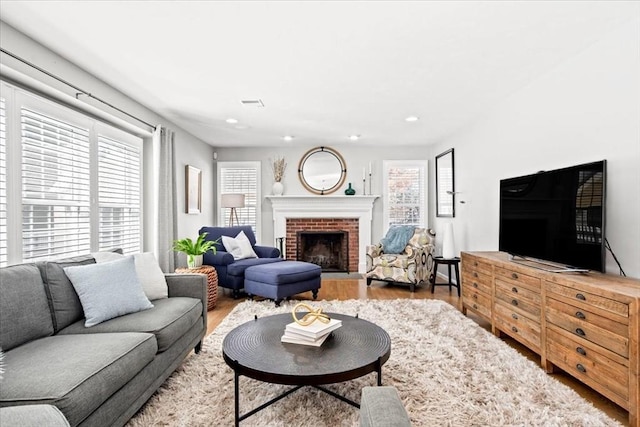 living room with a brick fireplace, wood finished floors, and recessed lighting