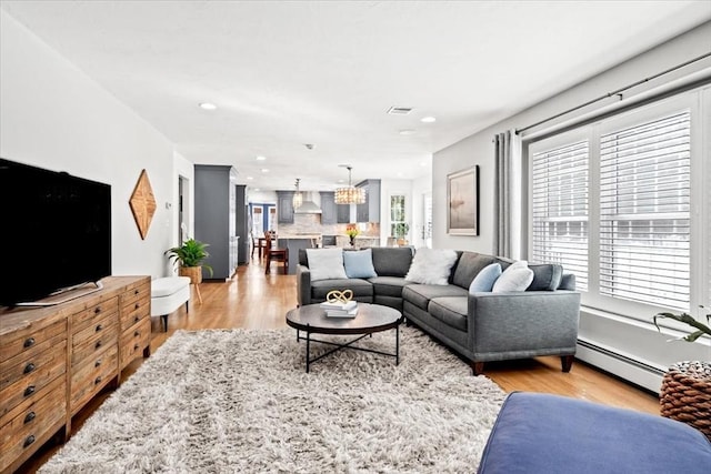 living room featuring a baseboard heating unit, light wood-type flooring, visible vents, and recessed lighting