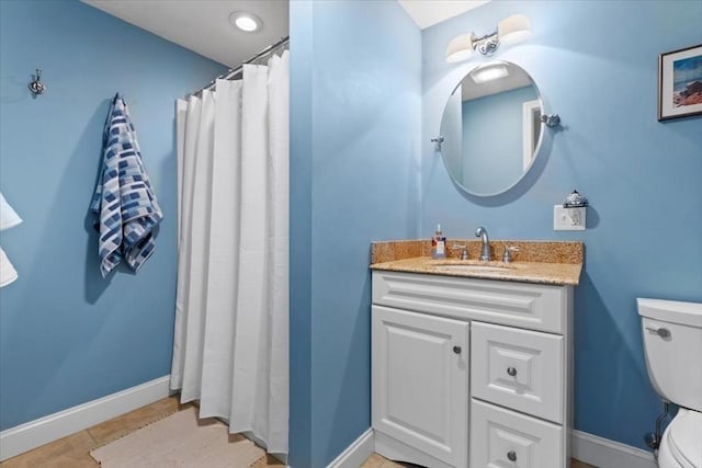 bathroom with toilet, tile patterned floors, baseboards, and vanity