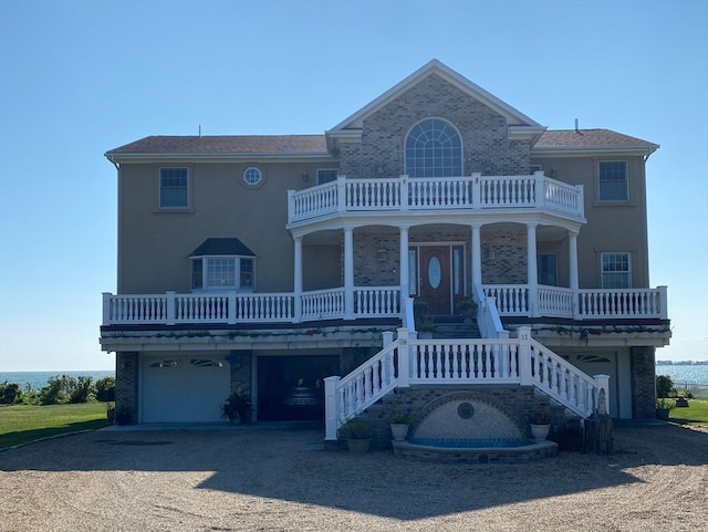 view of front of house with a balcony, a garage, a water view, and a porch