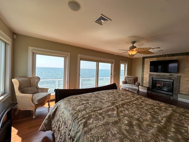 bedroom featuring dark wood-type flooring, ceiling fan, and a premium fireplace