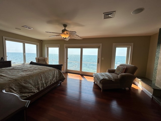 bedroom with access to exterior, ceiling fan, dark hardwood / wood-style floors, and a water view