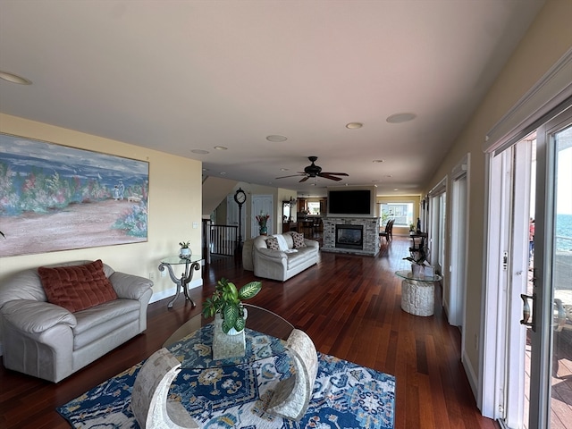 living room with dark hardwood / wood-style floors and a stone fireplace