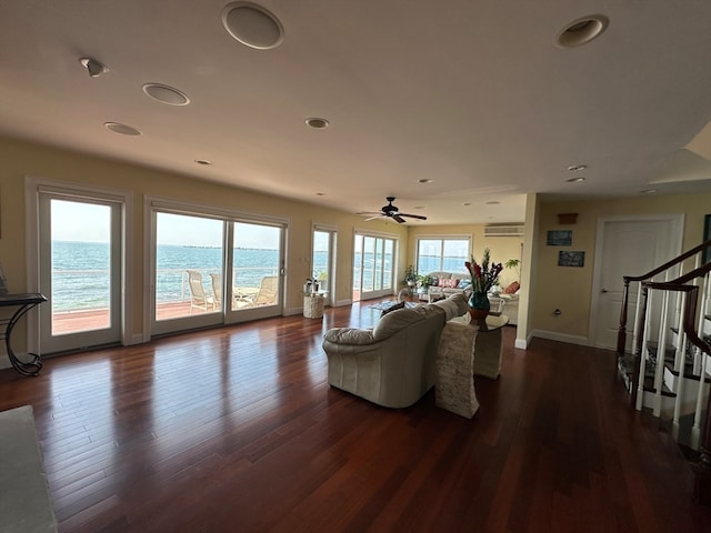 living room featuring ceiling fan, dark hardwood / wood-style floors, and a water view