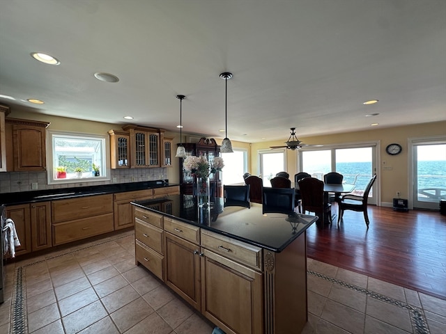 kitchen featuring backsplash, a center island, hardwood / wood-style flooring, ceiling fan, and a water view