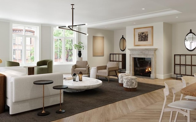 living room with light wood-style flooring, recessed lighting, baseboards, a glass covered fireplace, and crown molding