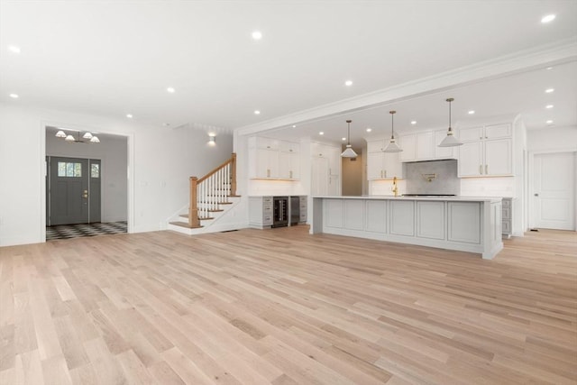 220 Atlantic St, Gloucester, MA 01930 - unfurnished living room with light wood-type flooring, stairs, recessed lighting, wine cooler, and a chandelier