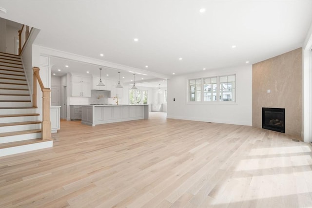 220 Atlantic St, Gloucester, MA 01930 - unfurnished living room featuring a fireplace, light wood-style floors, recessed lighting, stairs, and baseboards