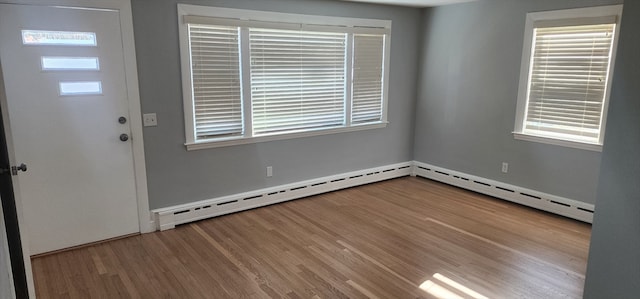 foyer entrance with baseboard heating and hardwood / wood-style floors