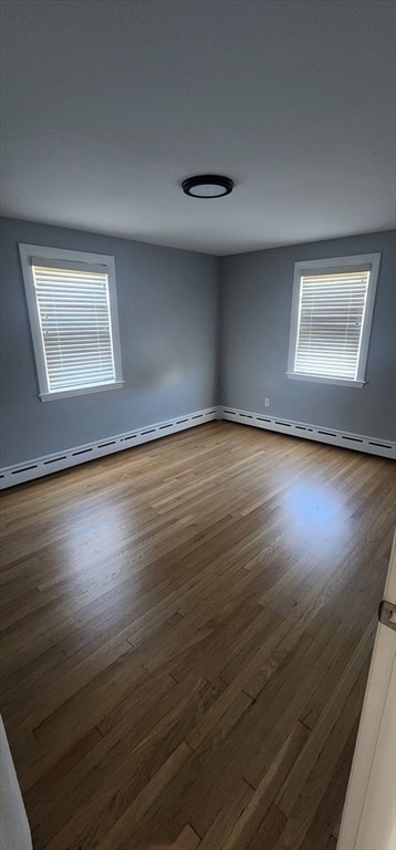 spare room featuring dark wood-type flooring and a baseboard heating unit