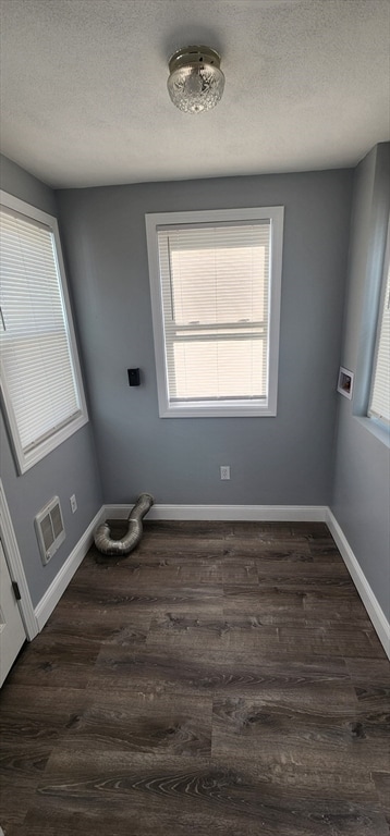 unfurnished room with a textured ceiling and dark hardwood / wood-style floors