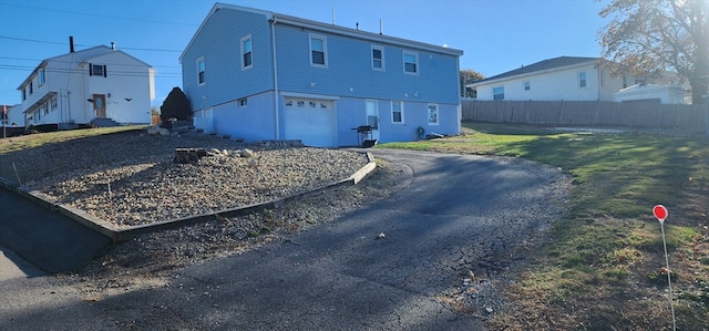 rear view of property with a garage and a lawn