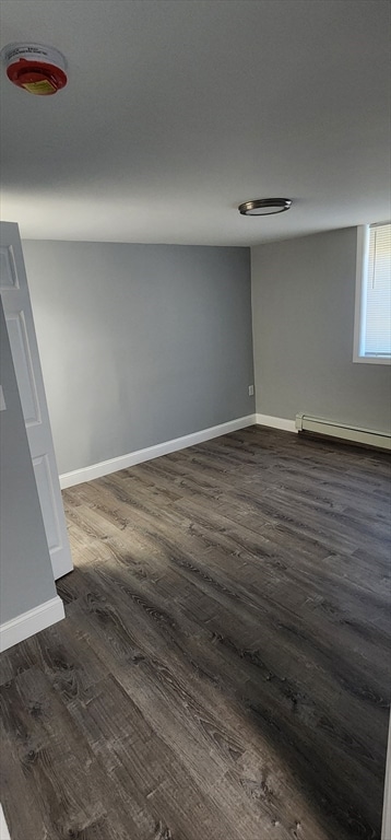 unfurnished room with a baseboard heating unit and dark wood-type flooring