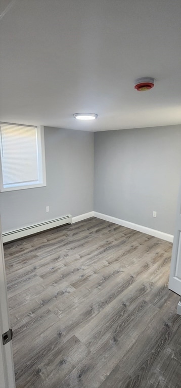 basement with hardwood / wood-style floors and a baseboard heating unit