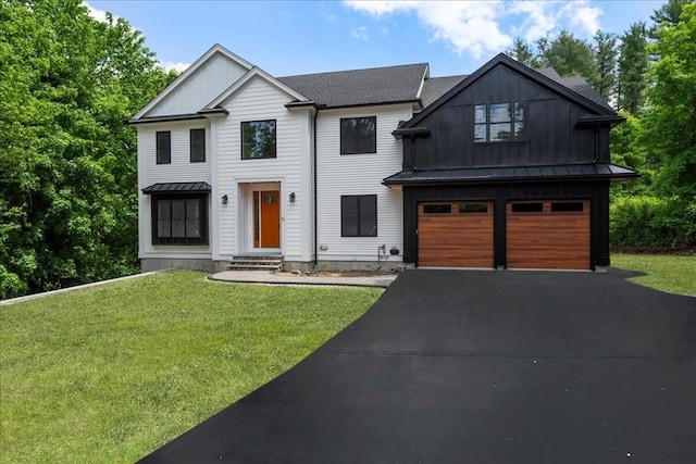 view of front facade featuring aphalt driveway, an attached garage, a standing seam roof, metal roof, and a front lawn