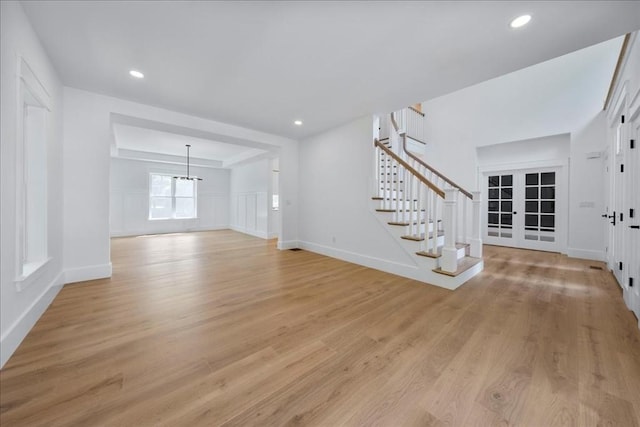 unfurnished living room featuring french doors, recessed lighting, light wood-style flooring, baseboards, and stairs