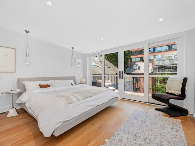 bedroom featuring light wood-type flooring, access to outside, and floor to ceiling windows