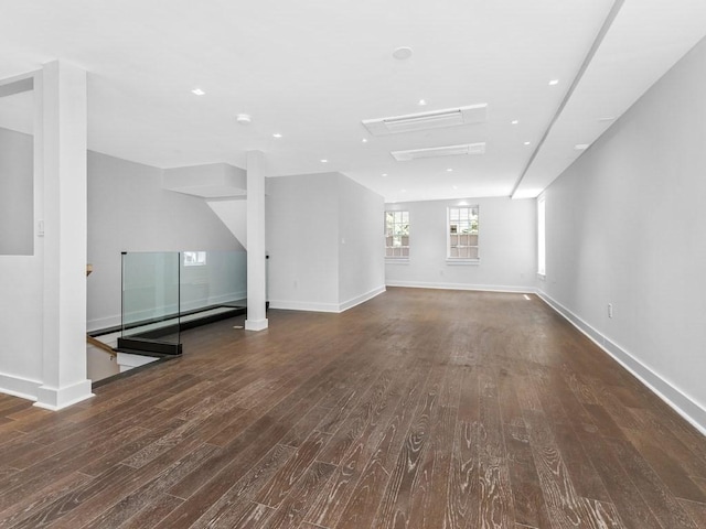 unfurnished living room with baseboards, a baseboard heating unit, and dark wood finished floors