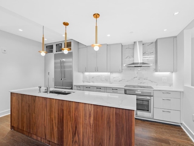 kitchen featuring wall chimney exhaust hood, dark hardwood / wood-style flooring, tasteful backsplash, appliances with stainless steel finishes, and decorative light fixtures