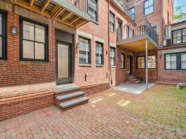 view of exterior entry featuring a balcony and a patio