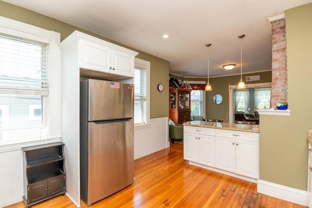 18 Dighton St Unit 18, Boston, MA 02135 - kitchen featuring freestanding refrigerator, white cabinets, light wood-style flooring, a wainscoted wall, and a peninsula