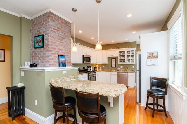18 Dighton St Unit 18, Boston, MA 02135 - kitchen featuring stainless steel appliances, a peninsula, light wood-type flooring, white cabinets, and ornamental molding