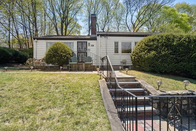 back of house with a lawn and a chimney