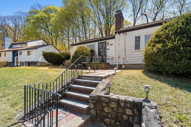 rear view of house featuring a lawn and a chimney