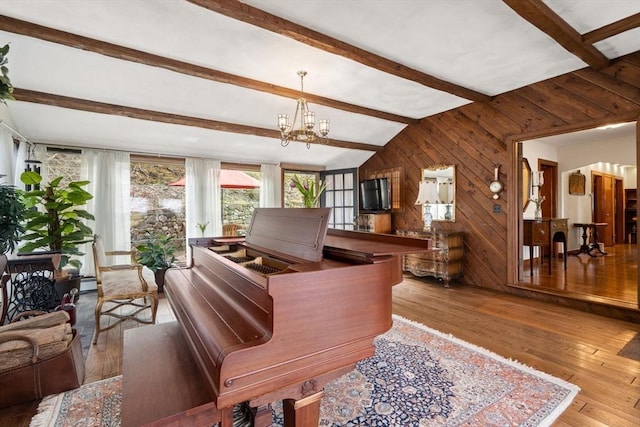 interior space with wooden walls, a notable chandelier, beam ceiling, a baseboard radiator, and hardwood / wood-style flooring