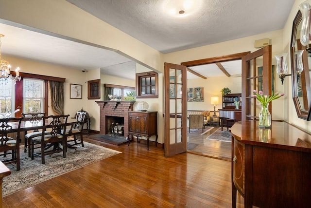 dining space featuring an inviting chandelier, plenty of natural light, wood finished floors, and a fireplace