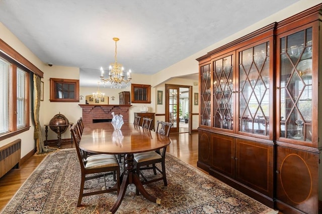 dining space with radiator heating unit, plenty of natural light, light wood-type flooring, and a notable chandelier