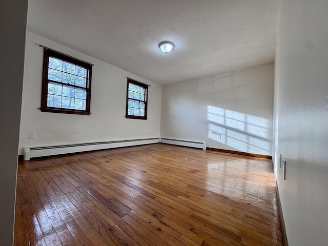 unfurnished room with a baseboard radiator and hardwood / wood-style floors