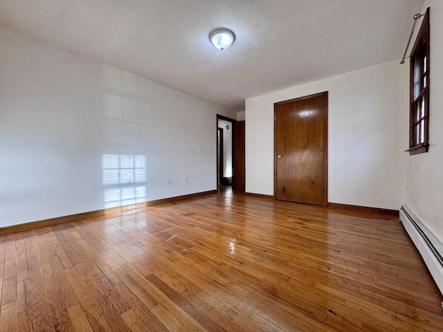 spare room featuring baseboard heating and hardwood / wood-style floors