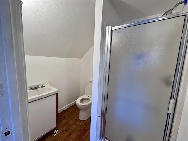 bathroom featuring lofted ceiling, toilet, wood-type flooring, walk in shower, and vanity