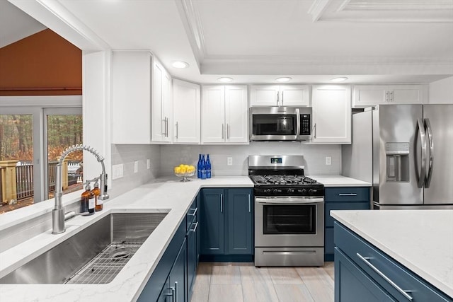 kitchen featuring blue cabinetry, appliances with stainless steel finishes, white cabinets, and a sink