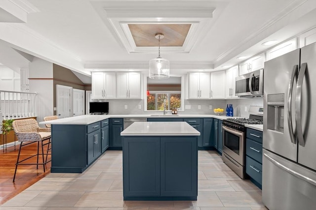 kitchen featuring a peninsula, light countertops, appliances with stainless steel finishes, blue cabinetry, and a tray ceiling