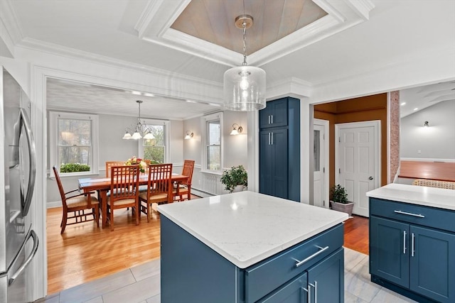 kitchen with stainless steel fridge, light wood-style floors, a kitchen island, crown molding, and blue cabinetry