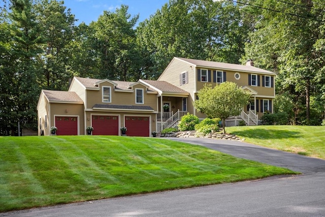 view of front of house with a garage, driveway, a front lawn, and a chimney