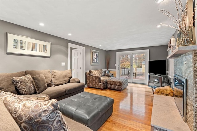 living area with light wood-style flooring, a fireplace, and recessed lighting