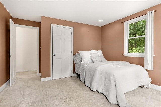 bedroom featuring light carpet and baseboards