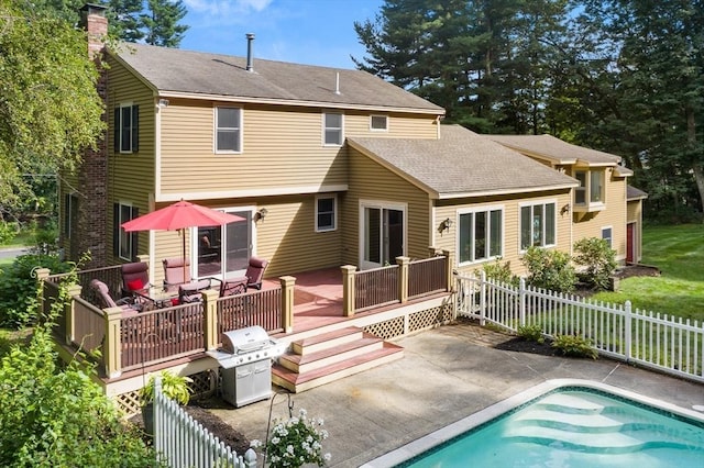 back of house with a fenced in pool, roof with shingles, a patio area, fence, and a deck