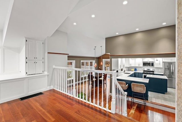 hall featuring lofted ceiling, recessed lighting, visible vents, a sink, and wood finished floors