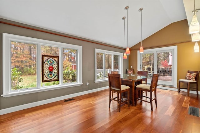 dining space with vaulted ceiling, wood finished floors, visible vents, and baseboards